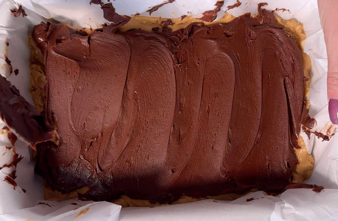 Rich chocolate and peanut butter dessert being spread in a parchment-lined tray at Mora