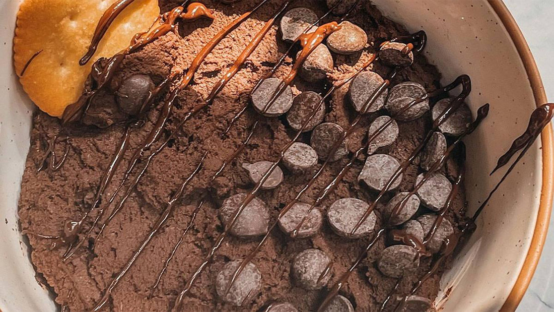 Chocolate mousse dessert topped with chocolate chips, chocolate drizzle, and a cracker in a bowl