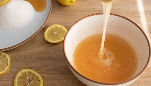 Honey mixture in bowl with lemon slices and sugar, natural ingredients on wood table