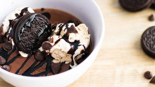 Chocolate dessert bowl with ice cream, cookies, chocolate sauce, and chocolate chips on wood table