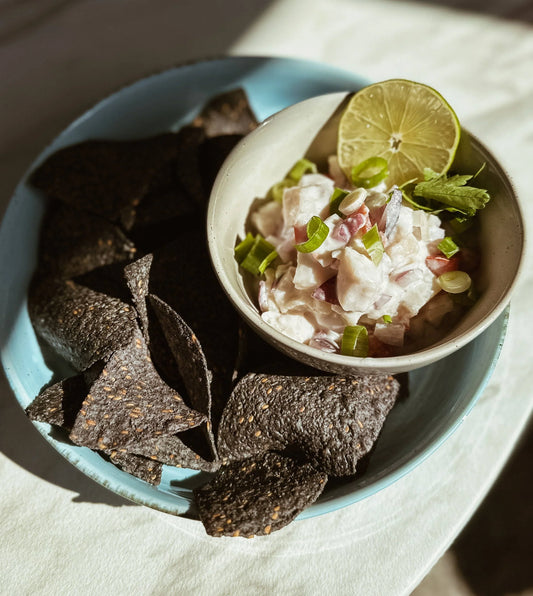 Blue corn tortilla chips with creamy dip garnished with lime and scallions on plate
