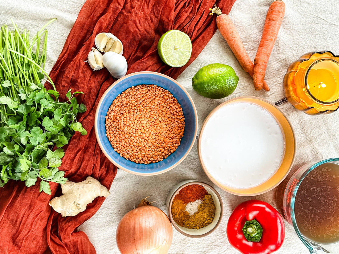 Colorful flat lay of fresh lentils, coconut milk, spices, vegetables, and herbs on a table for Mora recipe inspiration.