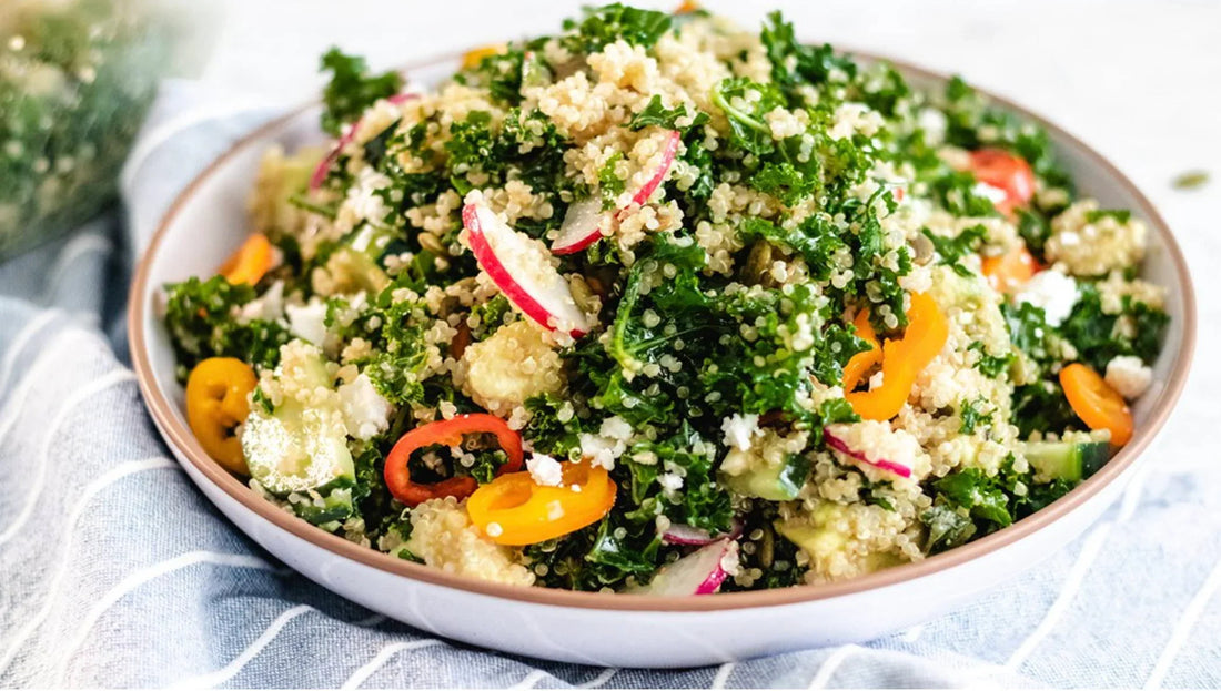 Fresh quinoa salad with kale, radishes, and peppers in a bowl on a striped cloth at Mora