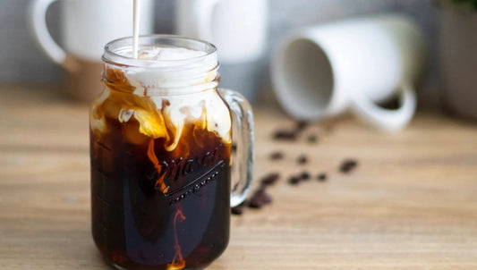 Cold brew coffee with cream in a mason jar, coffee beans on wooden table, Mora style